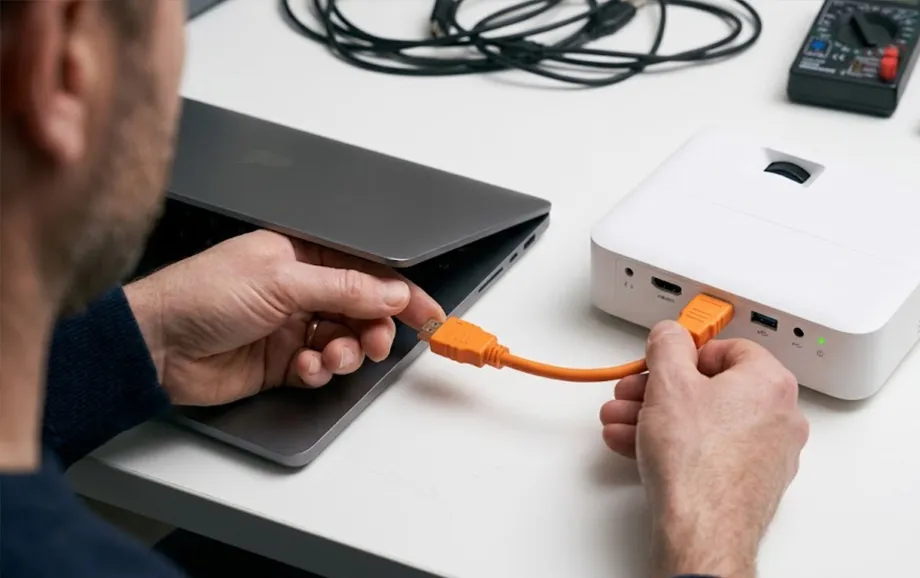Person checking a cable connection between a laptop and a projector