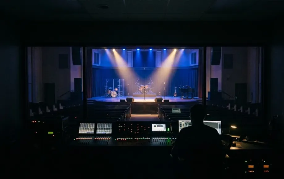 Media operator at a control desk overlooking an empty church and illuminated stage