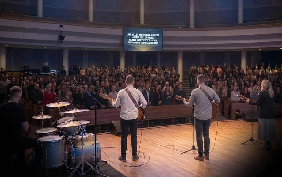Worship leaders facing the congregation and a rear screen displaying song lyrics