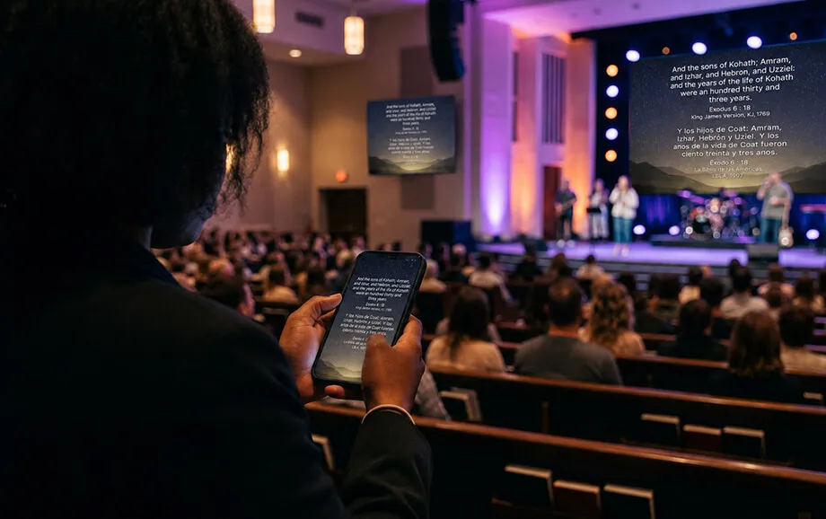 Person viewing text on a phone while the same passage appears on church screens